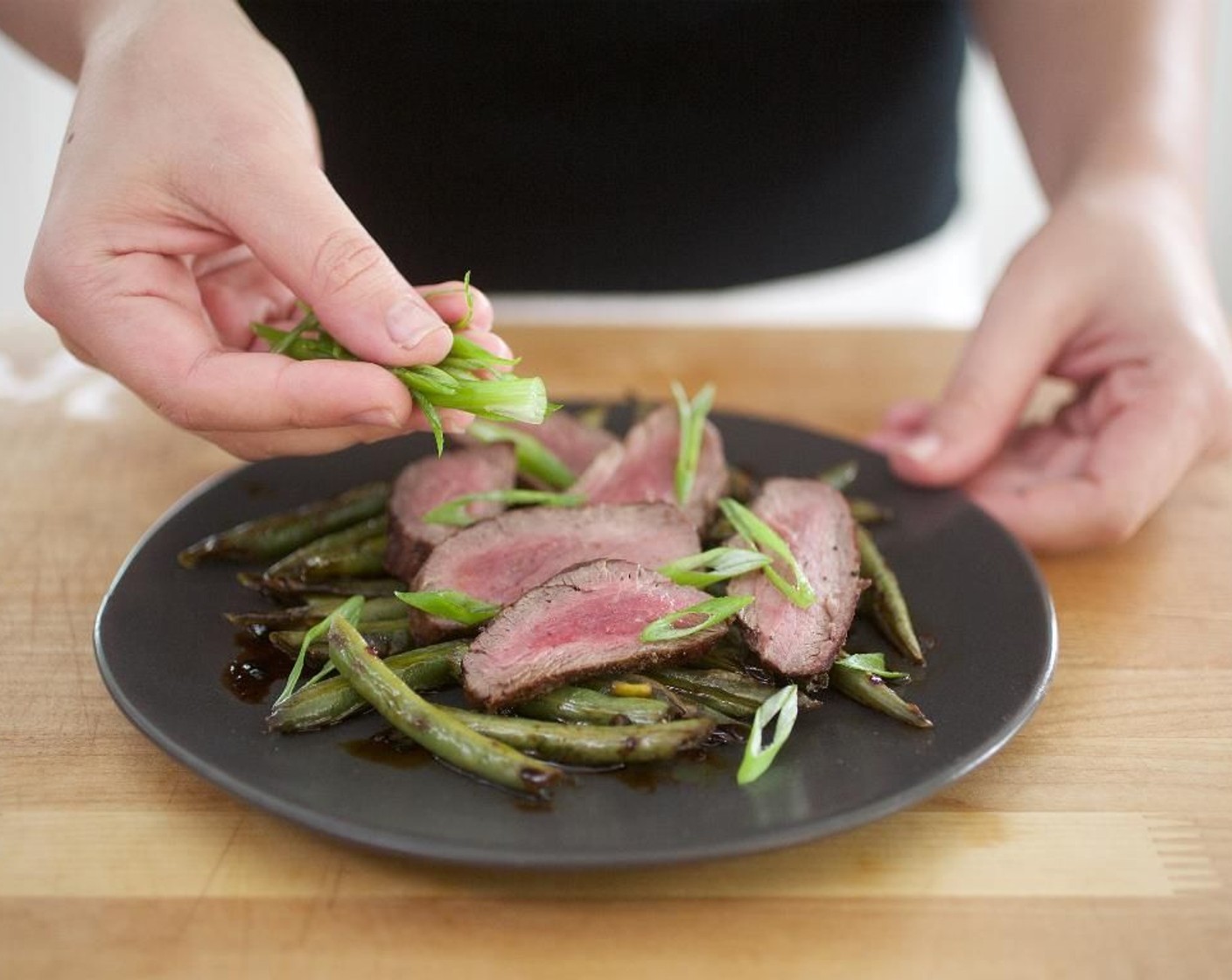 step 15 Divide the green beans evenly between two plates. Arrange the beef tenderloin slices on top of green beans. Garnish with scallions.