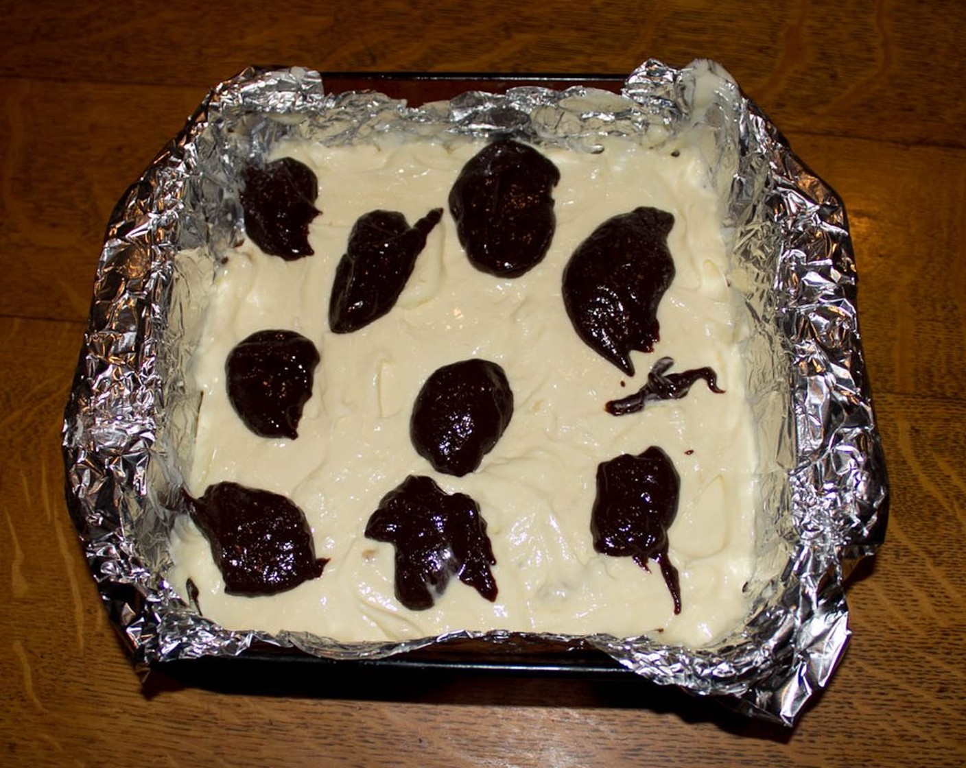 step 11 Spread cheesecake batter evenly over brownie batter in the pan. Take a spoon and place dollops of the reserved brownie batter over the cheesecake batter.