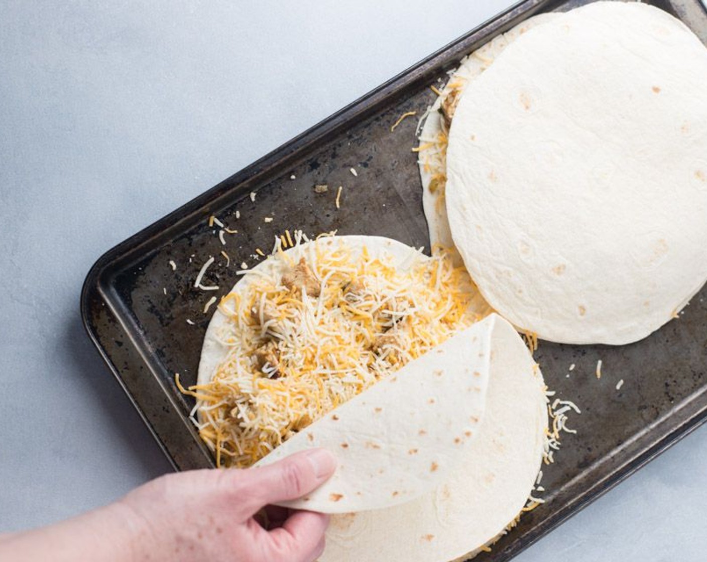 step 6 Lay another tortilla on top to finish that quesadilla. Repeat assembly for remaining quesadilla. Bake until cheese is melted and tortillas are crispy brown, for around 12 to 15 minutes.