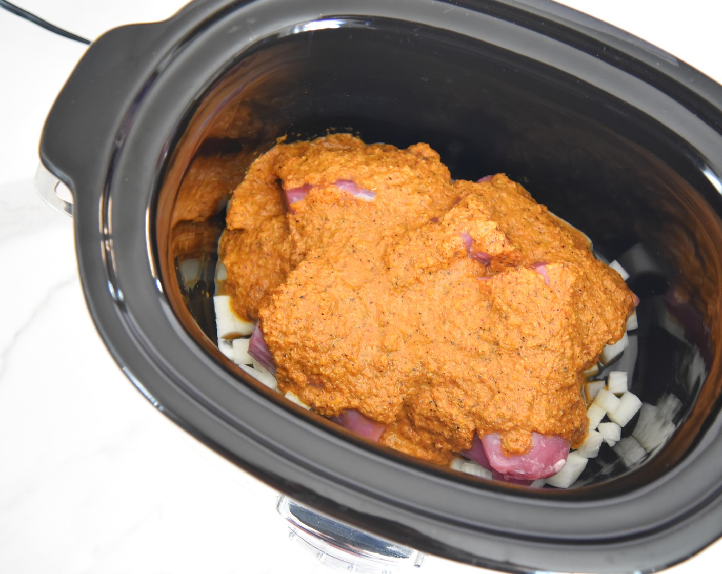 step 4 Empty any remaining frozen chopped onions into the bottom of the slow cooker. Top with the pork tenderloin pieces, then the sauce from the blender.