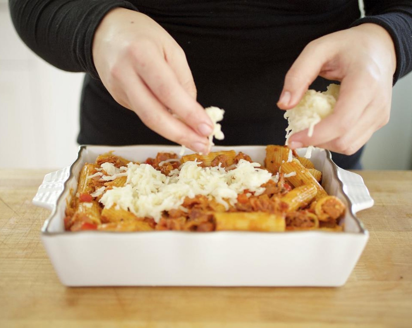 step 13 Pour the tomato cream sauce over the rigatoni.  Stir in the Parmesan Cheese (4 Tbsp). Transfer the pasta to a baking dish, sprinkle the Shredded Mozzarella Cheese (1 1/3 cups), evenly over the top and bake for 20 minutes until the cheese starts to turn a golden brown.