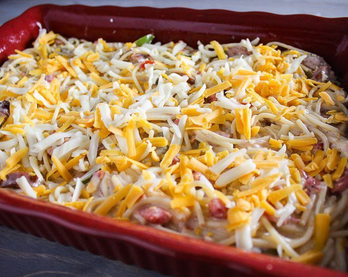 step 8 Fold in the sausage and vegetables. Transfer to the baking dish. Sprinkle with the remaining Medium Cheddar Cheese (3/4 cup) and Monterey Jack Cheese (3/4 cup).