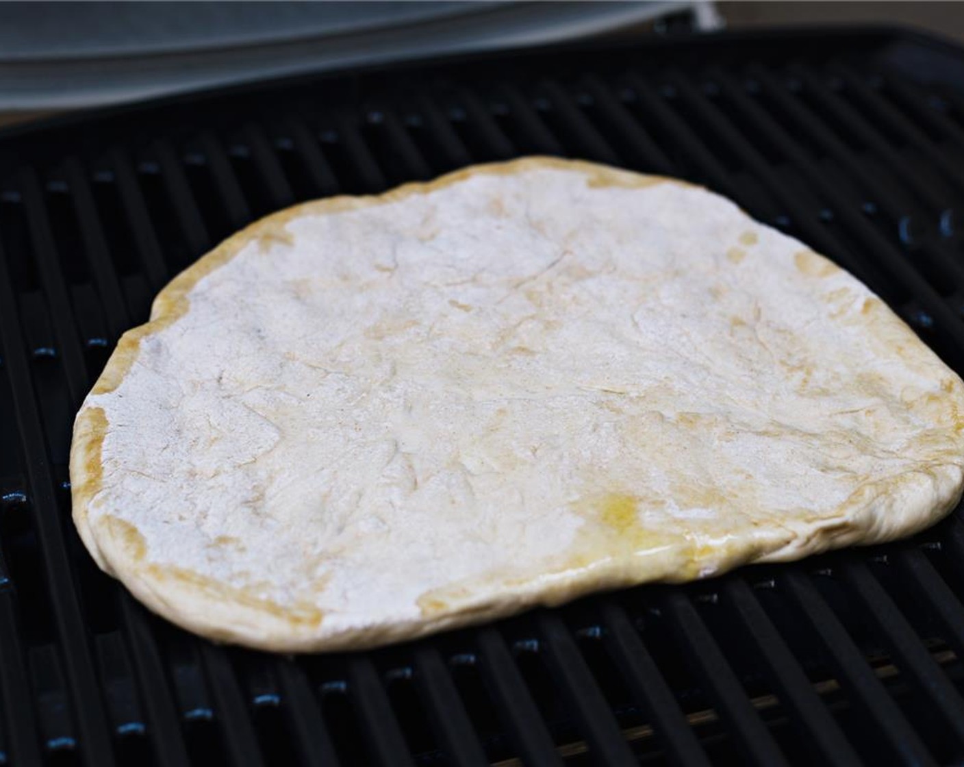 step 5 Put the pizza dough onto the grill, oiled side down. Grill on medium heat for five minutes.