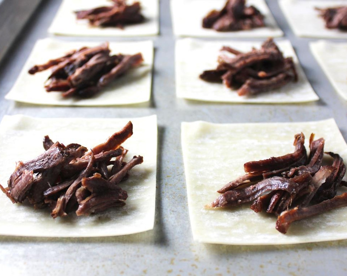 step 7 Bring a large pot of water to a boil. As you wait, place a small amount of pulled meat in each of the Wonton Wrappers (12) and fold them in half diagonally. Use water to seal the edges, making sure there are no air bubbles.