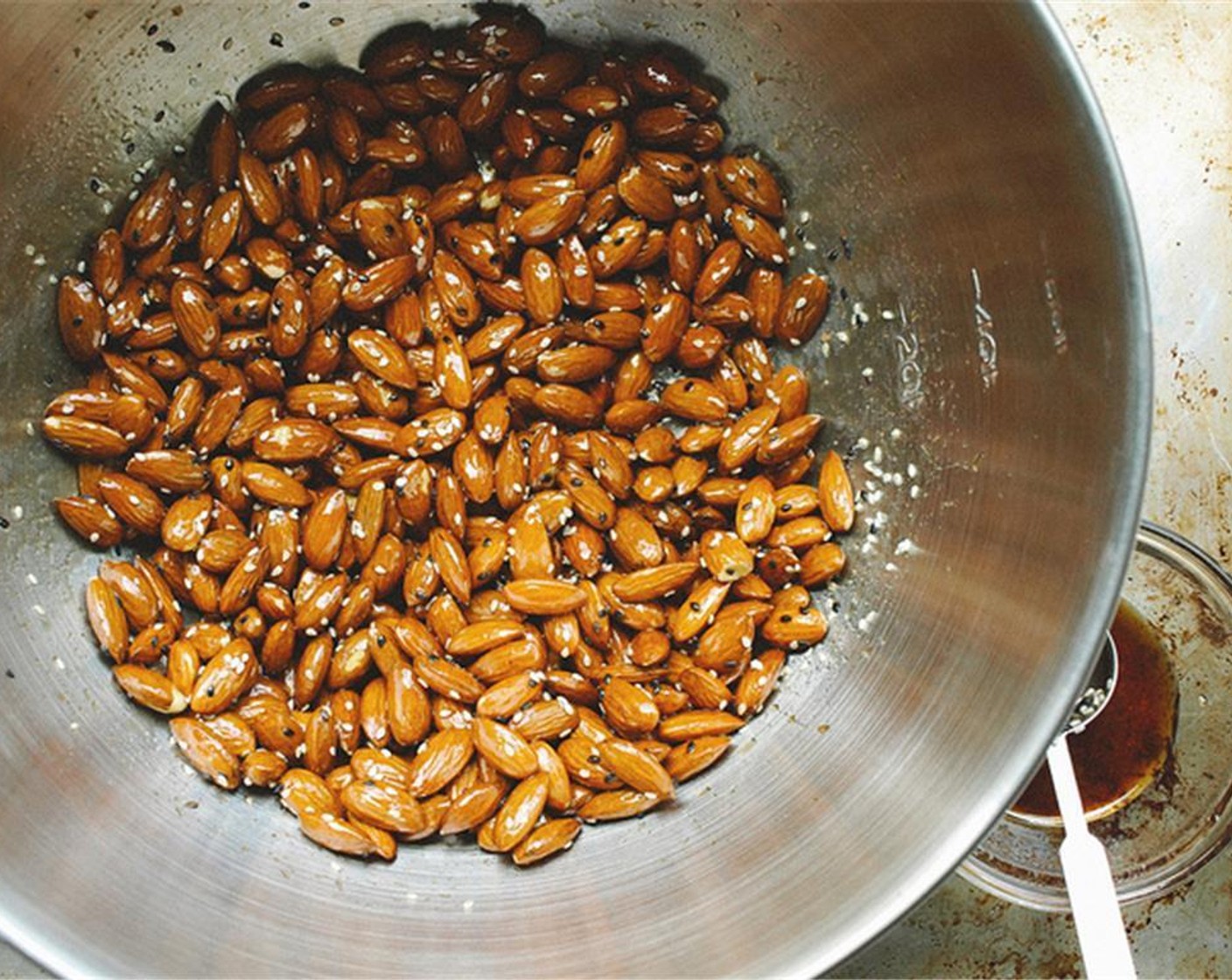 step 3 Put Raw Almonds (3 cups) in a large bowl, add the glaze and toss to coat. Add in White Sesame Seeds (1 Tbsp) and combine.