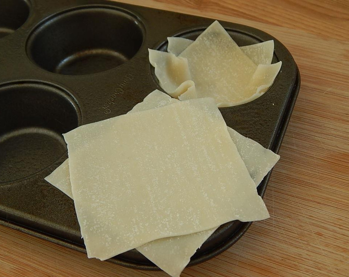 step 4 Spray a 6 hole regular muffin pan with non stick cooking spray. Use 2 Wonton Wrappers (12), push down into muffin cup, lightly spray the wonton wrappers.
