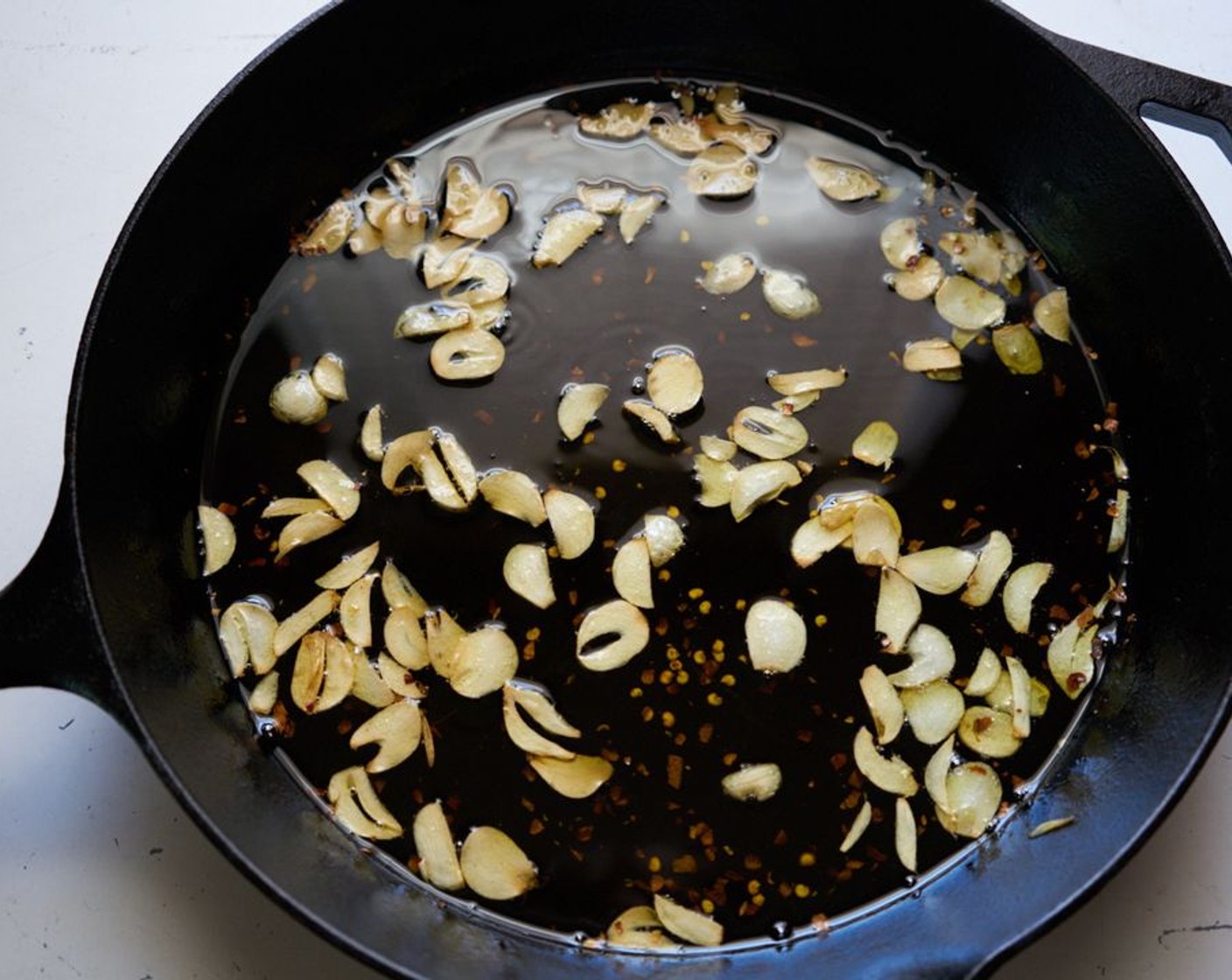 step 5 Add the Garlic (1/4 cup) and Olive Oil (1 1/4 cups) to a large cast-iron or other heavy skillet over moderately low heat. You are gently and slowly infusing the olive oil with the garlic flavor. Poaching the garlic, really. Stir occasionally, until the garlic is fragrant and has just barely started to brown.