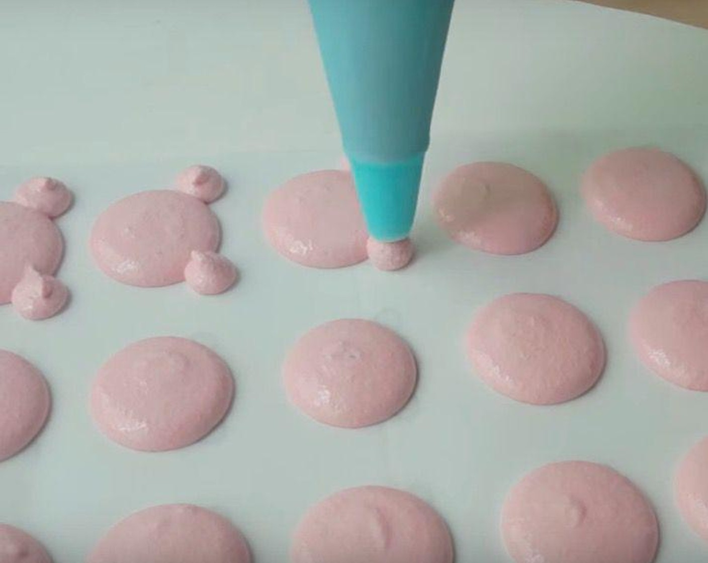 step 5 Transfer the batter to a piping bag with a round tip and pipe out macarons. Start by piping a large circle, about 2 1/2 centimeters, and two smaller circles for the ears. After piping, knock the bottom of the tray against a flat surface to get rid of air bubbles.