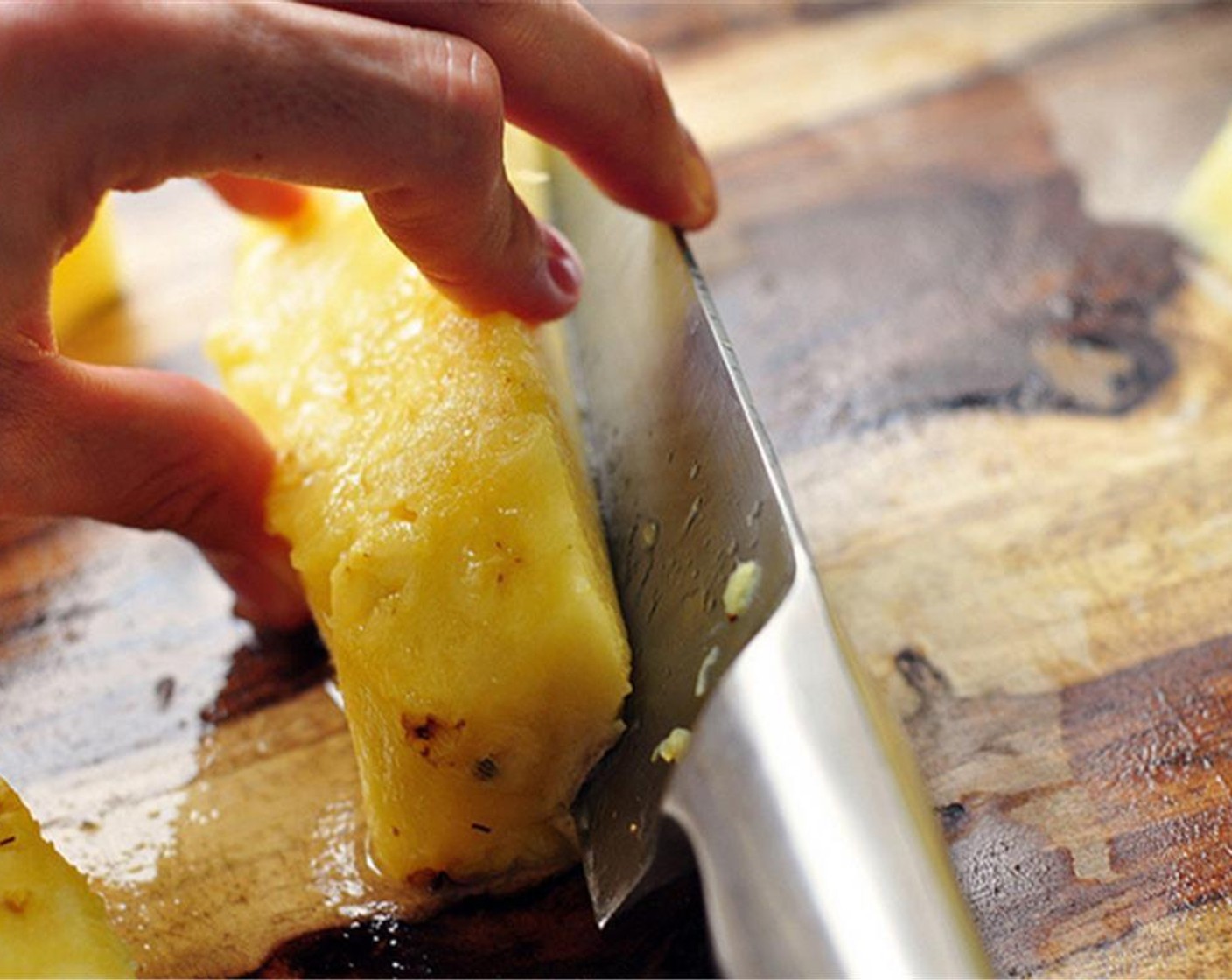 step 3 Turn the pineapple and continue cutting the rind away in strips. Cut away any brown eyes or sharp brown needles. Quarter the pineapple. Cut the core away at an angle, and finely chop the pineapple.