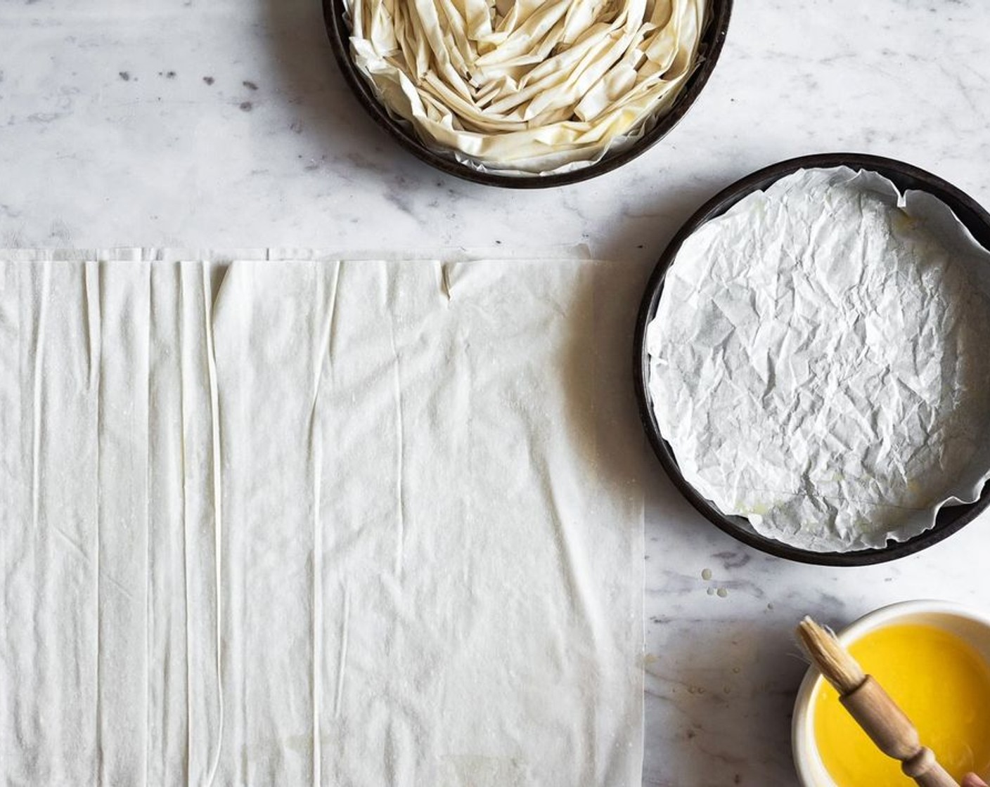 step 8 Place 1 sheet of Phyllo Dough (14 sheets) on a clean surface and brush it with Unsalted Butter (3/4 cup). Place another sheet of phyllo over the top of the first one and brush with butter. Use your fingers to scrunch up the phyllo long ways, into a loose ruffled strip (it's okay if the phyllo tears a bit).