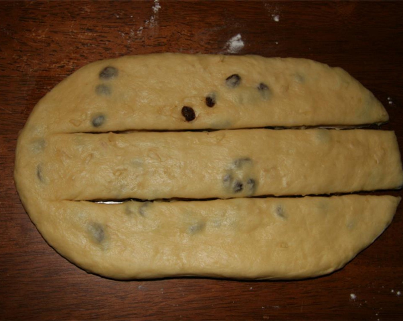 step 9 Return the dough to a work surface and knead briefly. Push or roll the dough into a rectangle about 14-inches long. Cut lengthwise into thirds, stopping each cut just before reaching the far side so that one short end of the rectangle remains intact.