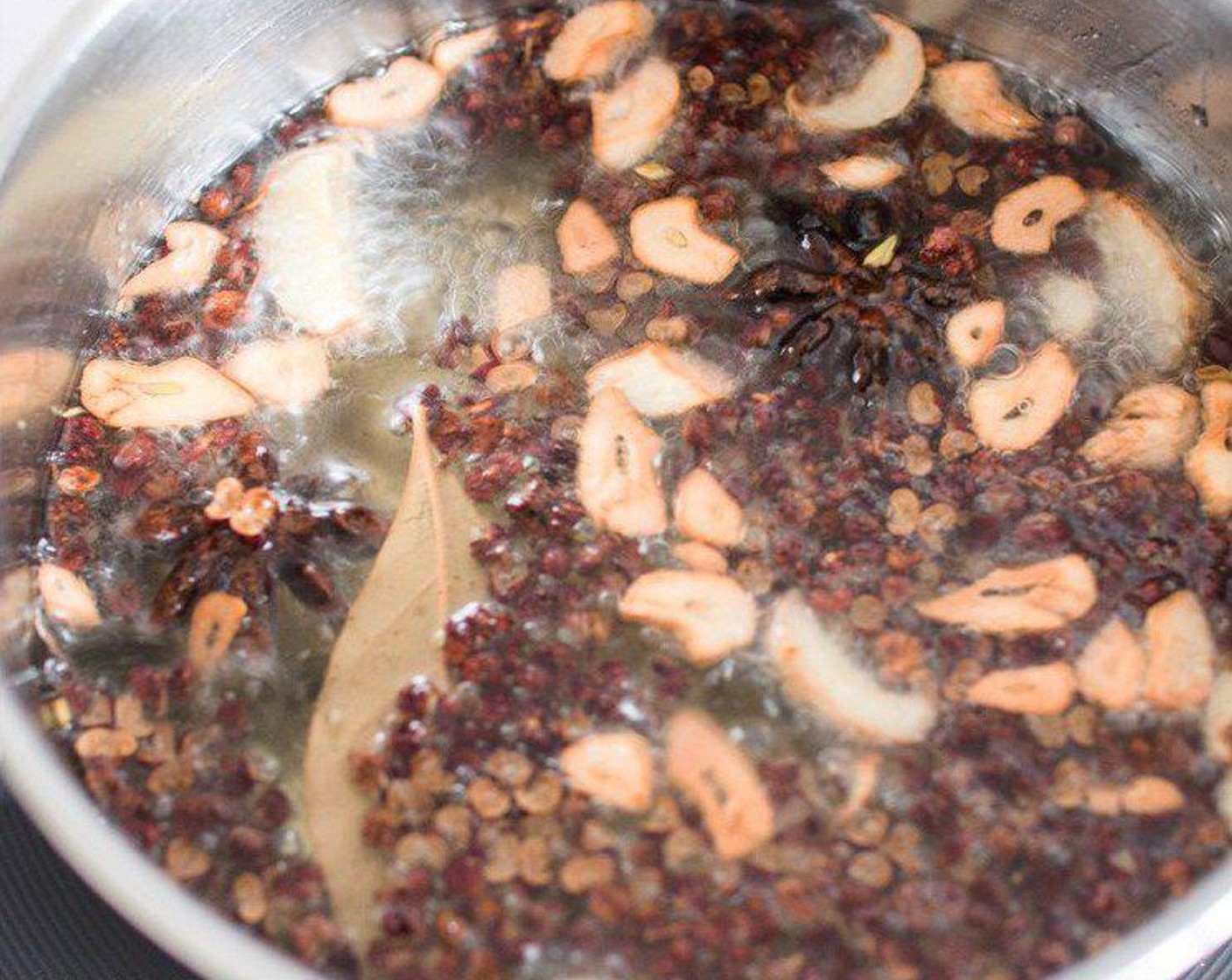 step 2 Heat the Oil (9 oz) in a saucepan over medium heat, add in Sichuan Peppercorns (1 Tbsp), Bay Leaf (1), Star Anise (2), Garlic (2 cloves), and Fresh Ginger (1 1/4 tsp) into the oil. Heat until the garlic turns golden in colour, that normally takes 3 to 4 minutes.
Remove the saucepan from the heat, set aside.