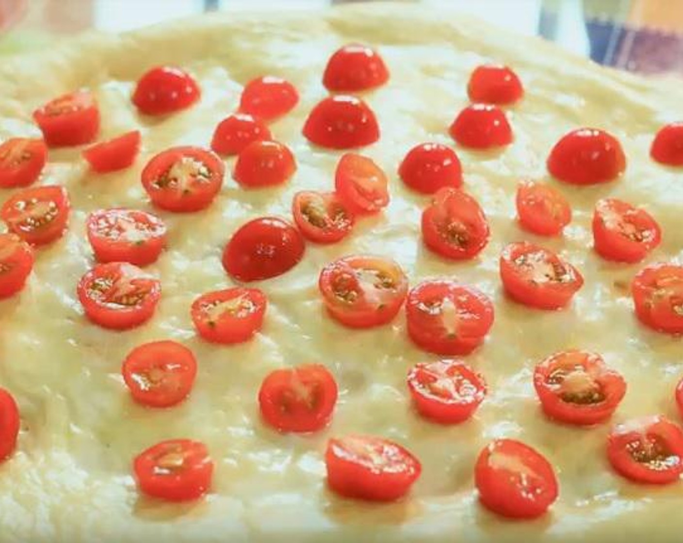 step 3 Flatten your dough into a circular shape, then sprinkle some Olive Oil (1 Tbsp) on top. Cut your Tomatoes (4) into pieces, and put them on top of the dough as well.