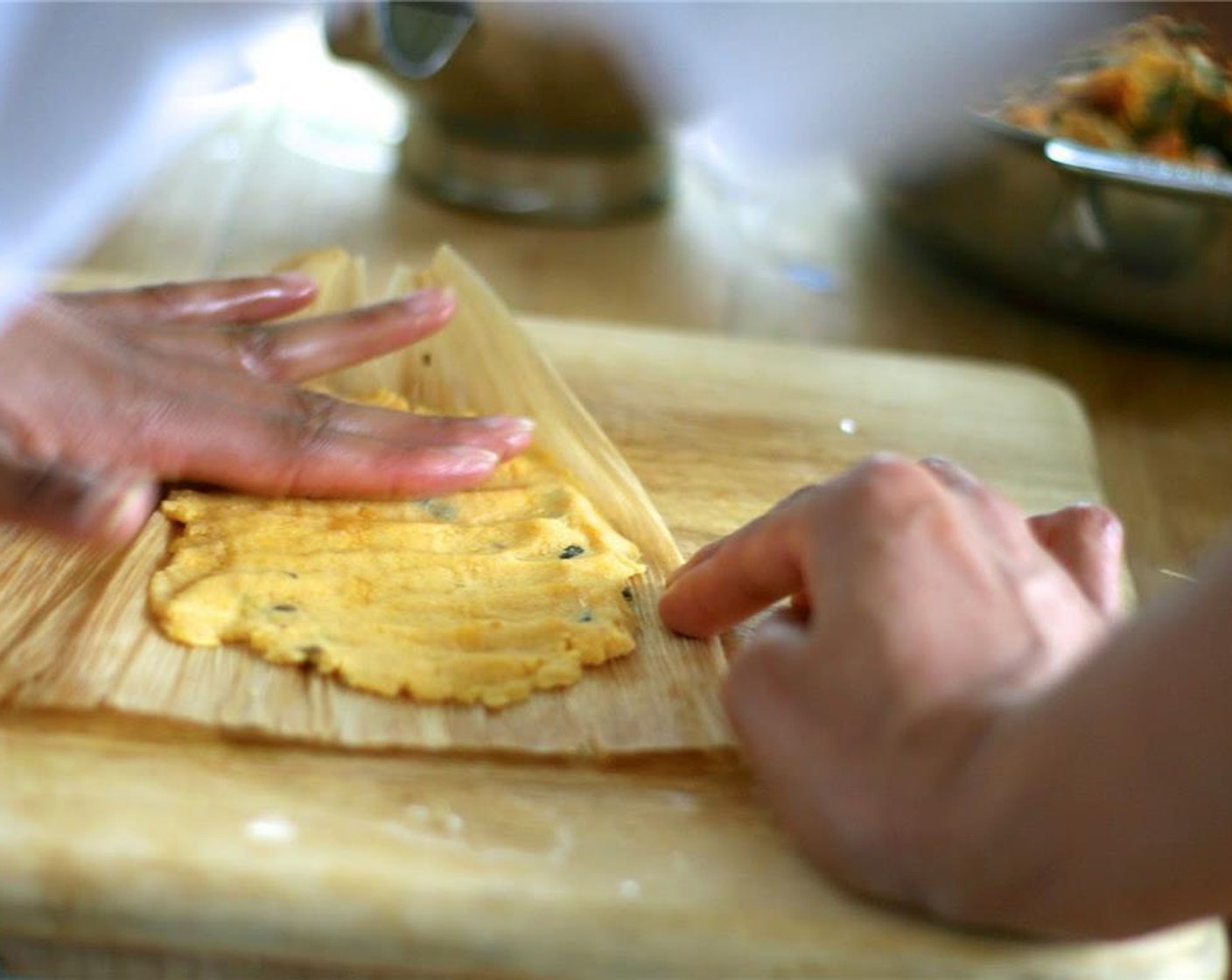 step 8 Lay out a corn husks, overlapping a second husk if needed. Spread about 1/3 cup of masa dough onto the husk and press into a square, about 1/4-inch thick, leaving room around the edges. Spoon 1-2 tablespoons of desired filling down the center.