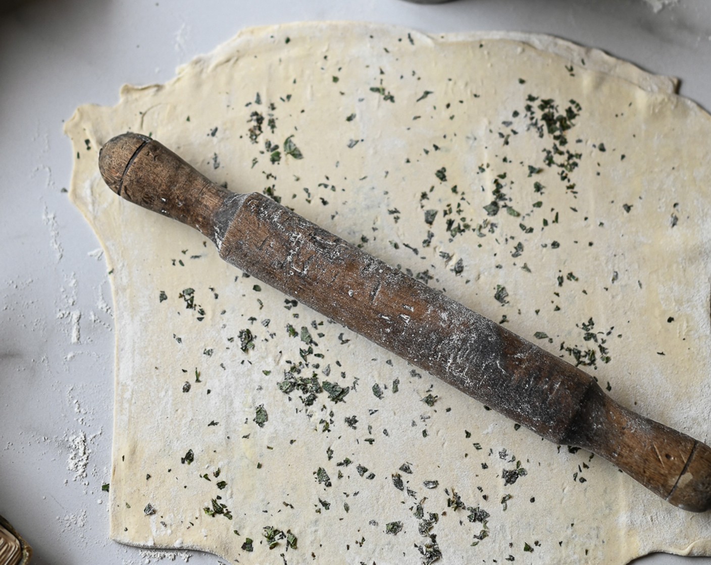 step 6 On a floured surface, roll out the Puff Pastry (1). Sprinkle over the Fresh Rosemary (1 sprig) and Fresh Thyme (1 sprig) and use the rolling pin to embed them into the pastry.