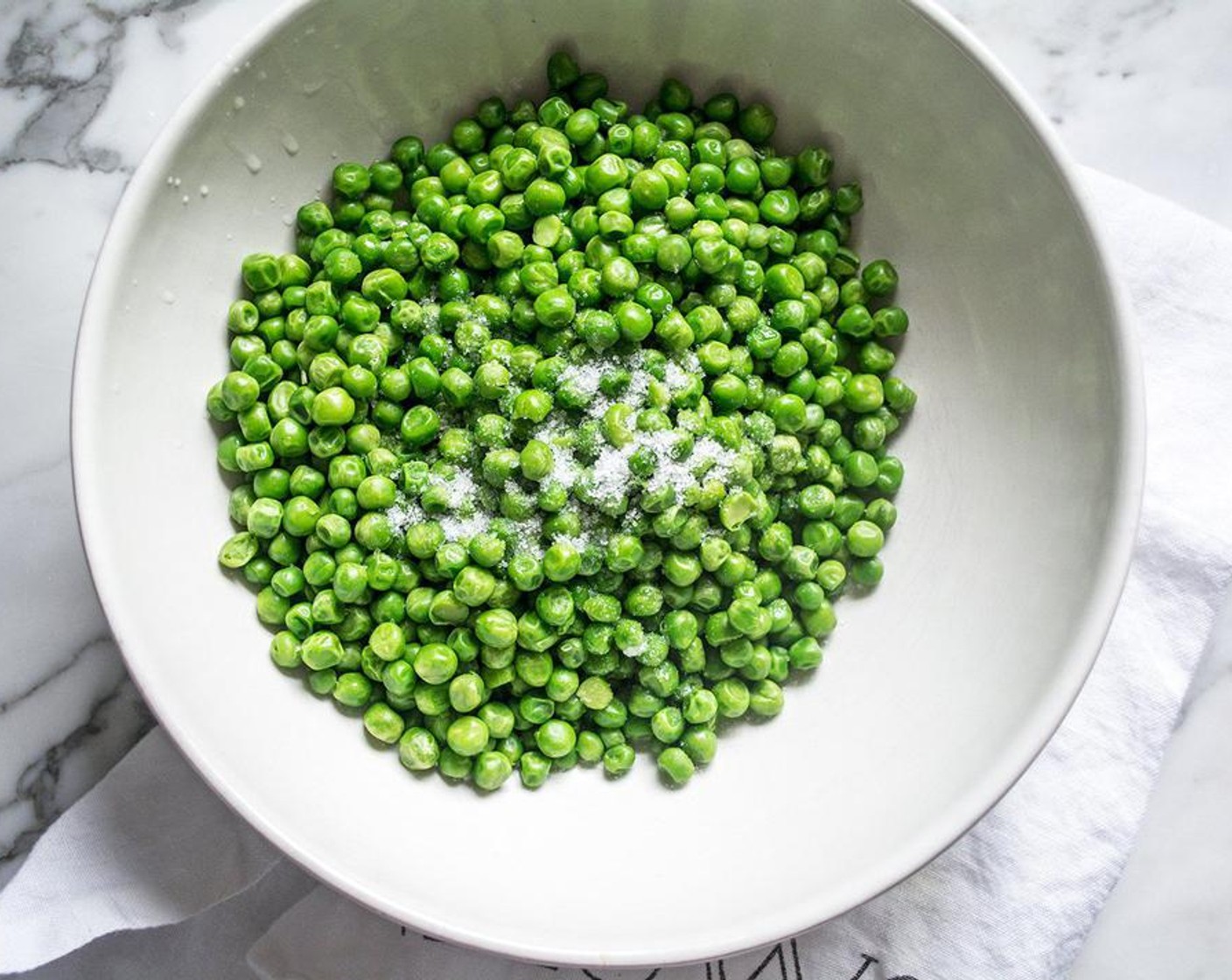 step 3 Add thawed and dried peas to a large bowl, then drizzle with Coconut Oil (1/2 Tbsp). Sprinkle with Sea Salt (1 tsp) and toss to coat, then spread back out in a single layer on a large baking sheet lined with aluminum foil.