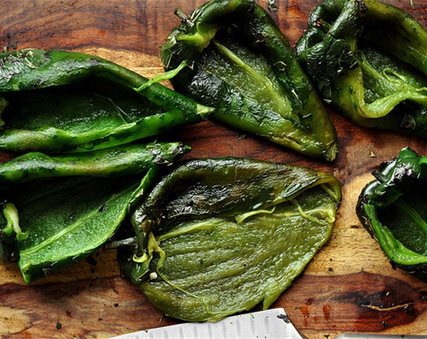 step 9 Once cool, carefully remove the skin by scraping the outside with the blade of your knife. Remove the seeds from the poblano peppers (keeping the stems in tact) by making a slit down the middle and scooping out the seeds. Set peppers aside.