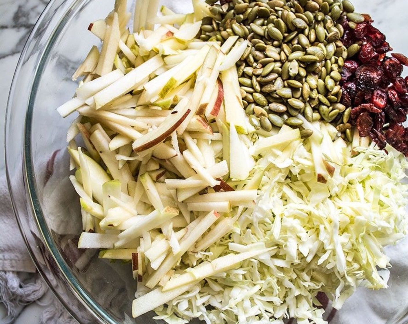 step 1 Add Green Cabbage (6 cups) and Apples (4 cups) to a large bowl, followed the Dried Cranberries (3/4 cup) and Pepitas (1/2 cup). Toss to combine.