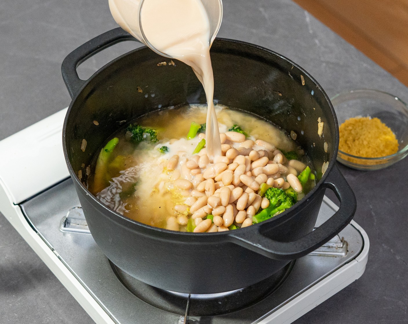 step 3 Add the Cannellini White Kidney Beans (1 can), Vegetable Broth (2 cups), Oat Milk (1 cup), and Nutritional Yeast (2 Tbsp). Bring to a boil, and turn off the heat. Use a stick blender to purée the soup.