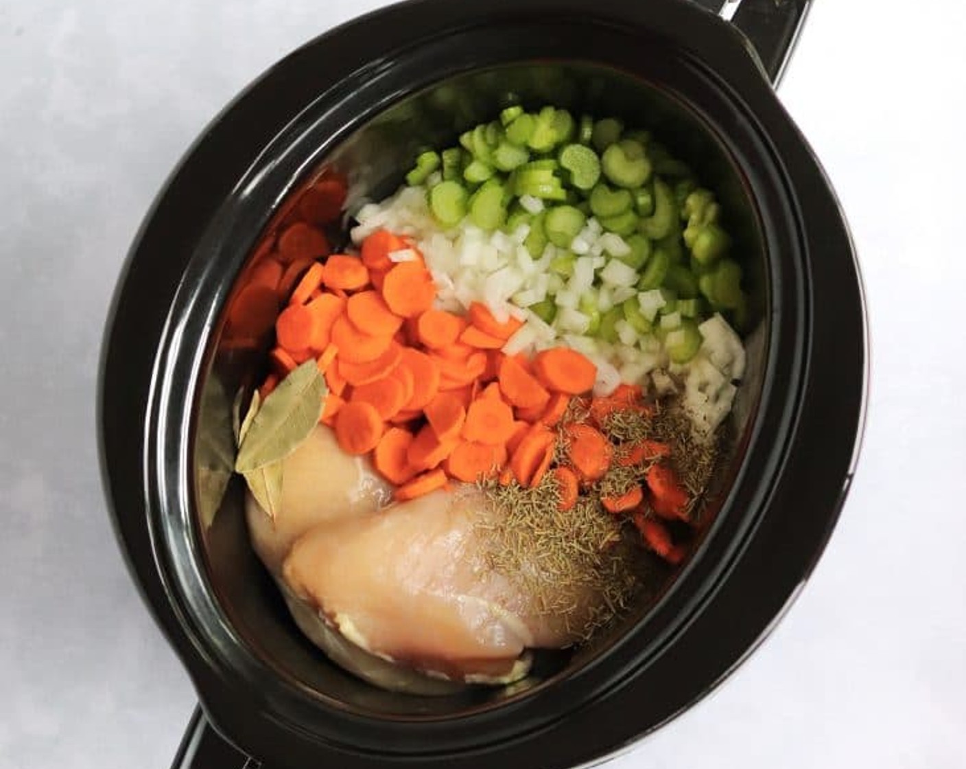 step 1 In a large slow cooker, add the Yellow Onion (1), Carrots (4), Celery (4 stalks), Garlic (4 cloves), Chicken Stock (8 cups), Boneless, Skinless Chicken Breasts (2), Bay Leaves (2), Dried Thyme (1 tsp), and Dried Rosemary (1 tsp). Season with {@10:} and Ground Black Pepper (to taste). Cook on low for 6-8 hours.