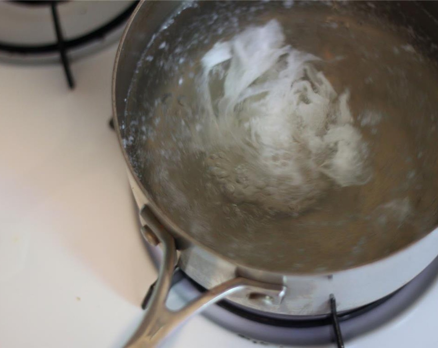 step 9 When the water is boiling, add remaining Rice Vinegar (2 Tbsp). Stir to create a vortex, then quickly crack the Eggs (4) into the swirling pot. Cook for about three minutes, remove with a slotted spoon, and place on a paper towel to dry. Repeat.