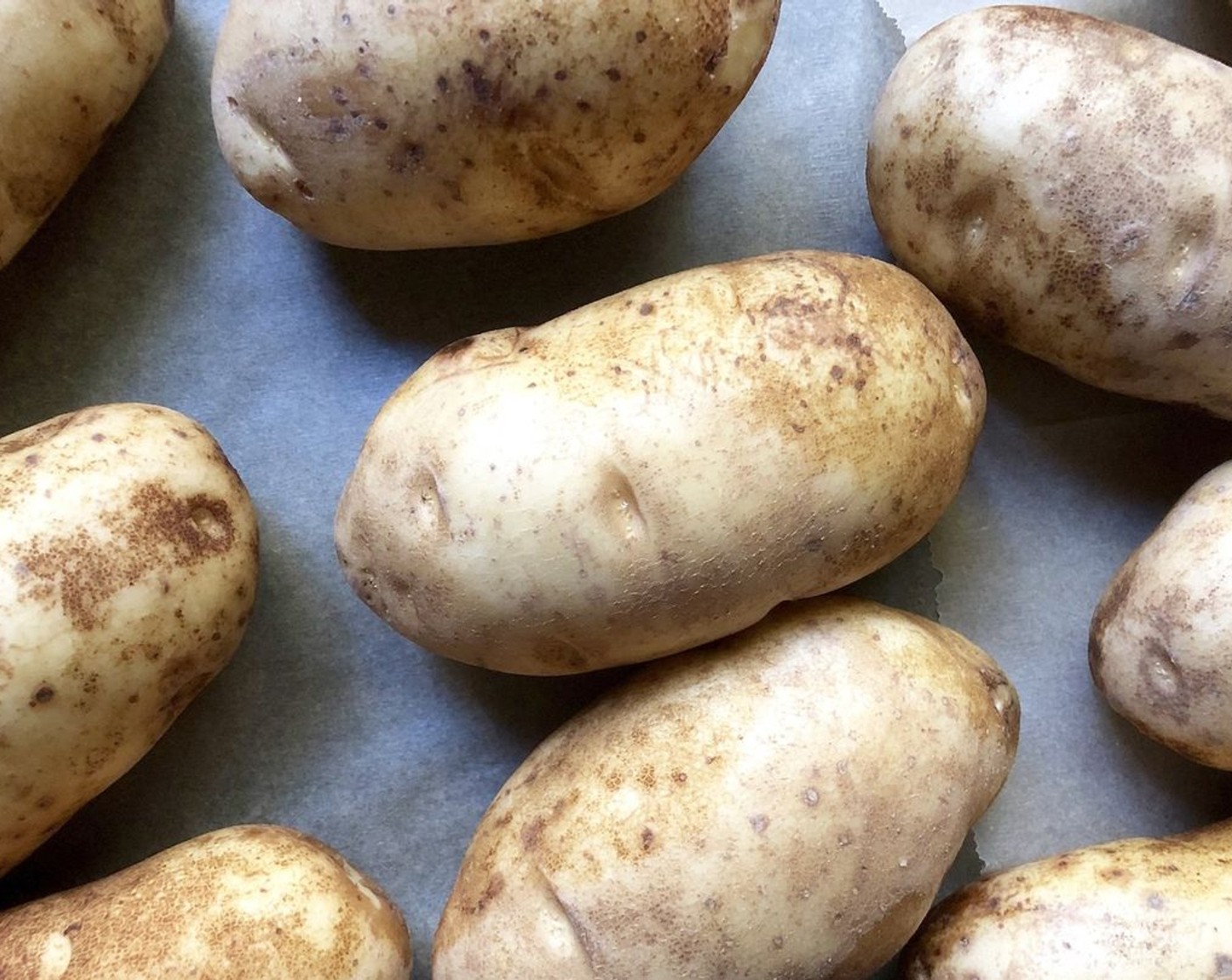 step 2 Rinse and dry the Potatoes (4). For crispy skin, rub a small amount of olive oil all over each potato. For softer skin, wrap each individual potato in tin foil. Place the potatoes on a baking tray and bake for about 60 minutes until they are soft throughout. Test for doneness by pricking them with a fork.