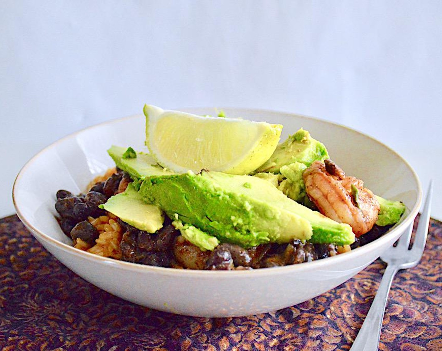 step 7 Once the rice is ready, take it off of the heat and fluff it up with a fork. Scoop a generous helping of the rice into 4 bowls. Divide the shrimp mixture evenly among the 4 bowls on top of the rice.  Top each burrito bowl with Avocados (2) and Lime Wedges. Serve immediately and enjoy!