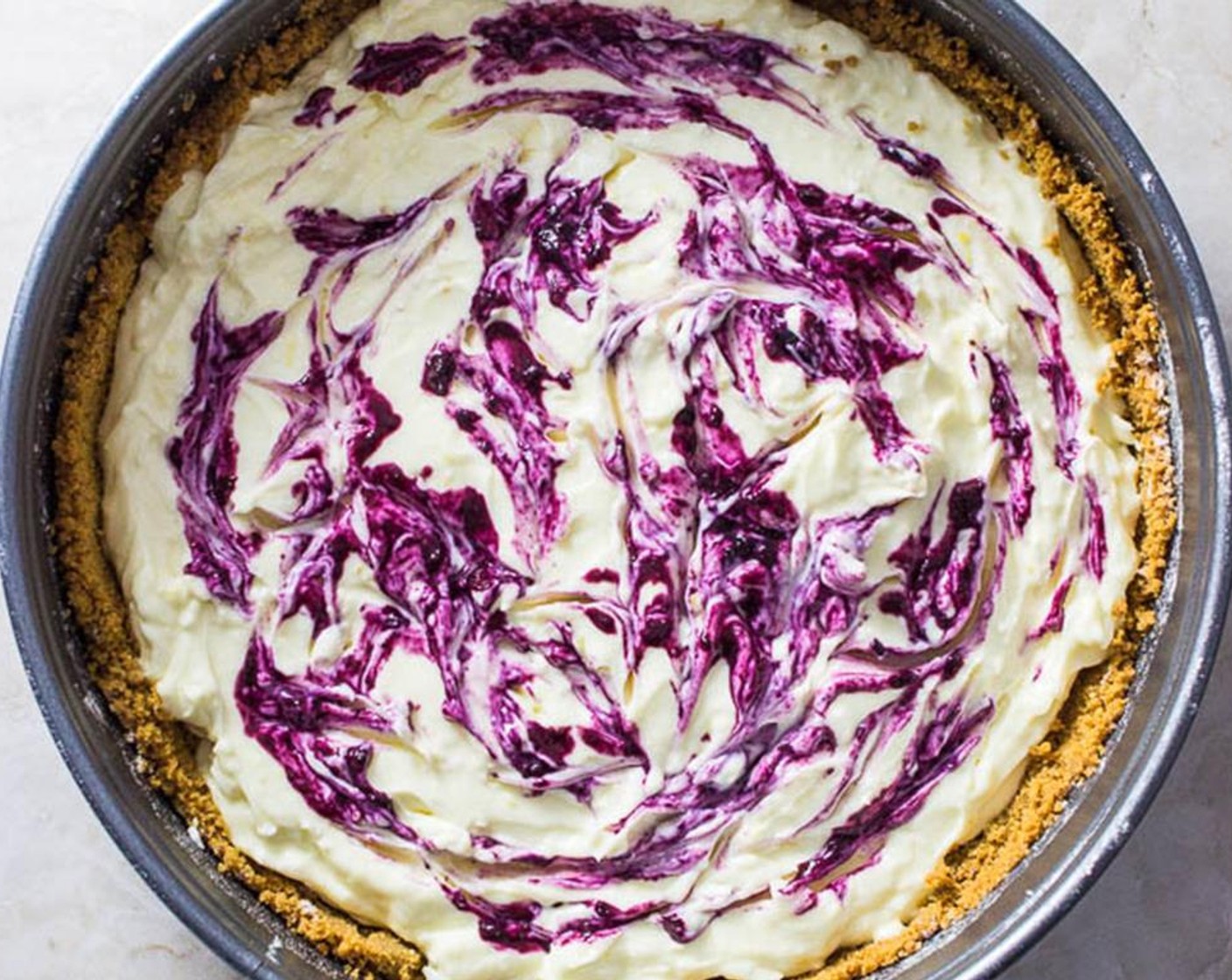 step 9 Pour spoonfuls of the blueberry liquid over the cheesecake, and use a knife to add swirl patterns.