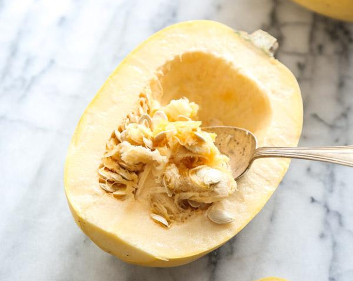 step 2 Using the largest chef’s knife you have, cut the Spaghetti Squash (1) in half lengthwise. Scoop out the seeds and stringy bits from the center cavity.