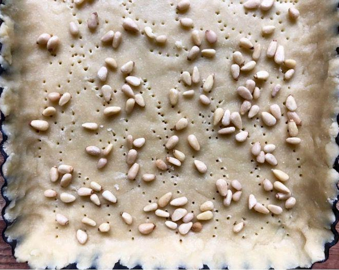 step 5 Using the tines of a fork, prick dough all over and sprinkle the Pine Nuts (1/4 cup) evenly over the surface. Line the pastry with a double thickness of foil.