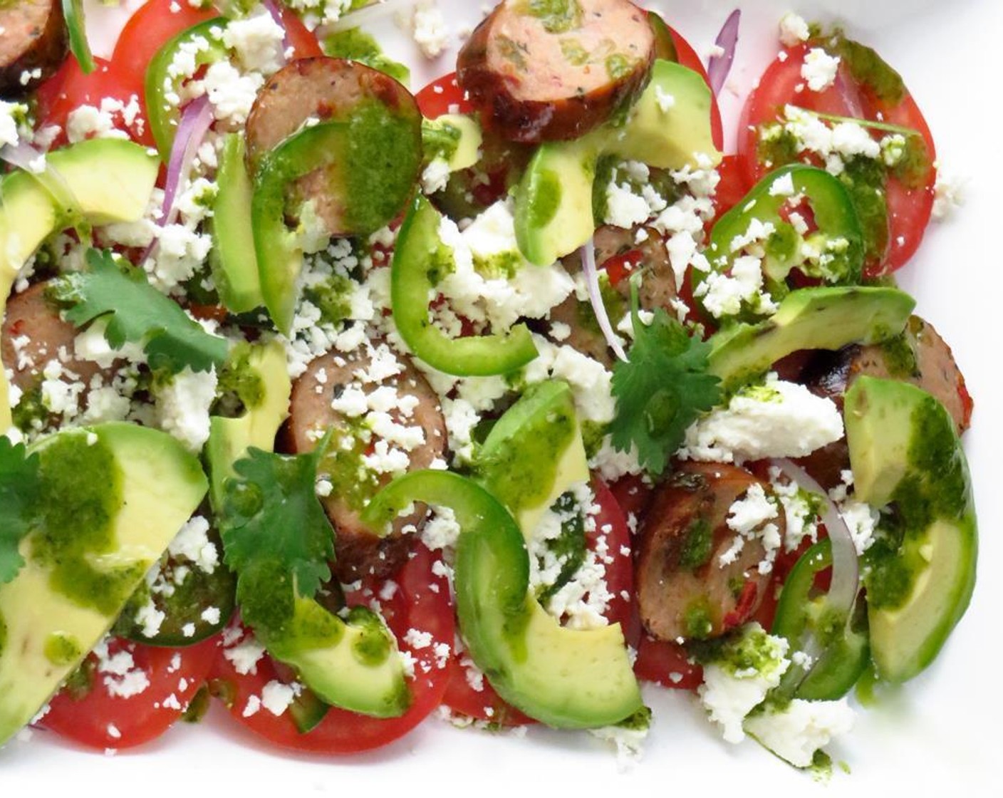 step 4 On a large platter, assemble salad by layering small red onion, plum tomatoes, jalapeno pepper, sausage slices, avocado, queso fresco, and cilantro leaves. Garnish with Lime (1) and drizzle with cilantro dressing. Serve and enjoy!