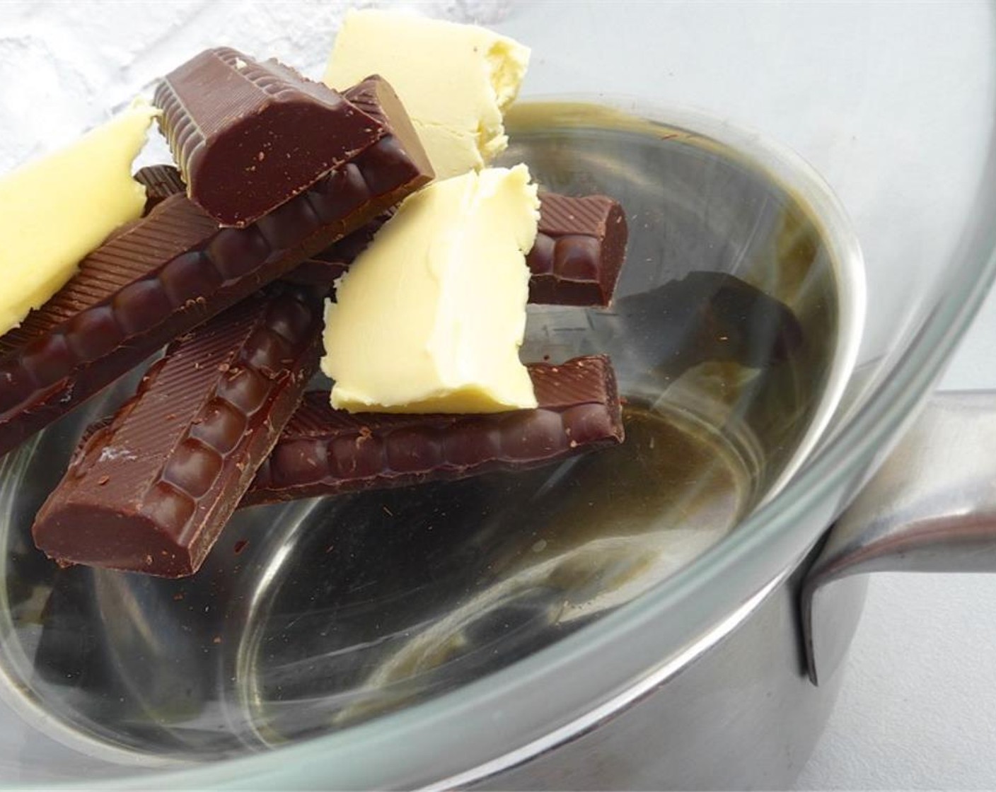 step 2 Bring a small pan of water to a boil over medium heat. Put a larger glass bowl on top. Break up the Dark Chocolate (1 cup) into smaller pieces. Chop up the Butter (1 cup). Add both chocolate and butter to the glass bowl and let them melt over the boiling water.