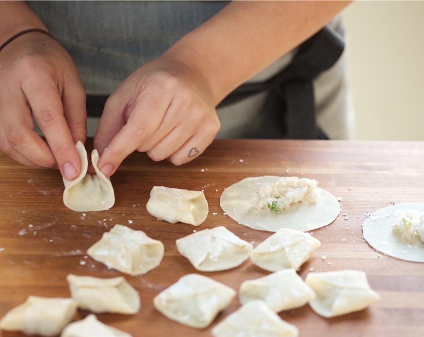 step 6 Brush the edges of the dumpling wrappers with water and fold the wrappers in half. Take the corners and bring them together to make a "big hug" wrapping. Place in the fridge until ready to use.