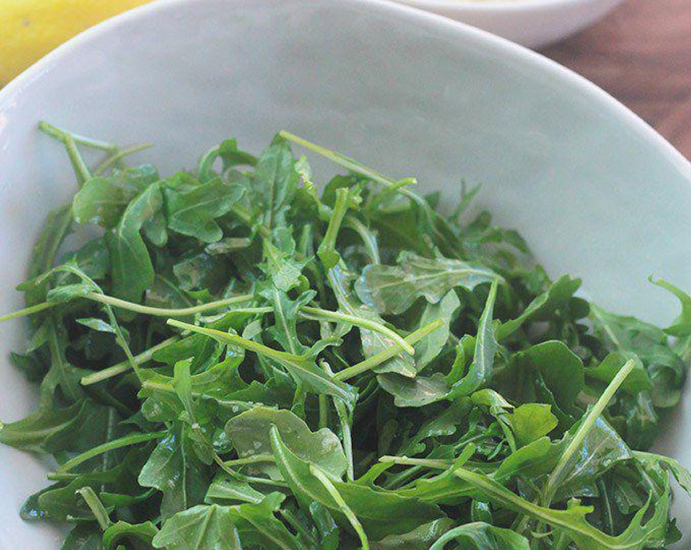 step 4 While pizza is in the oven, place Arugula (4 cups) in a large bowl, drizzle with Extra-Virgin Olive Oil (1 Tbsp) and juice from Lemon (1/2). Season with Salt (to taste) and Ground Black Pepper (to taste).