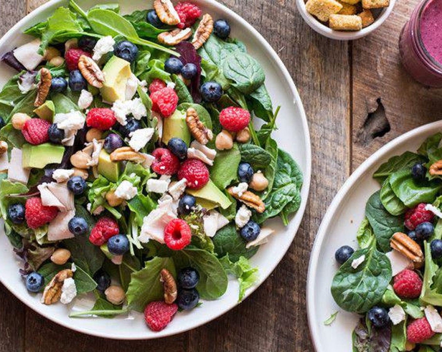 step 1 Layer Romaine Spring Mix (2 cups), Fresh Spinach (2 cups), Fresh Blueberry (1/2 cup), Fresh Raspberry (1/2 cup), Pecan Halves (1/4 cup), Canned Chickpeas (1/2 cup), Avocado (1/2), Deli Turkey (4 slices), and Goat Cheese (4 Tbsp) in large bowls or plates, dividing the items evenly.