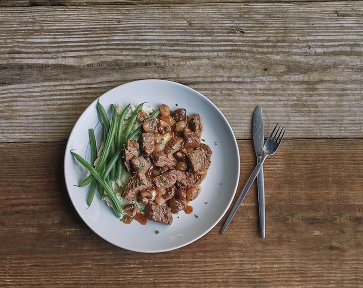 step 16 Plate mashed potatoes in the center of two plates. Serve the beef bourguignon over potatoes garnished with chopped chives with green beans on the side.