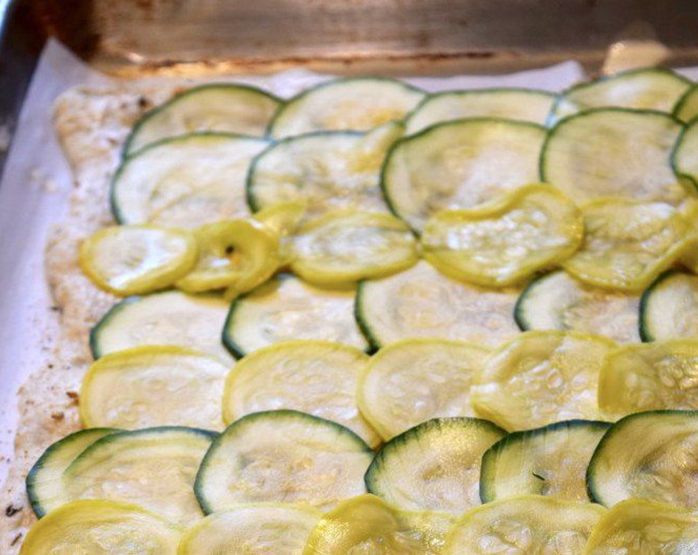step 6 Press the zucchini/squash slices dry and then place them all across the pizza dough leaving about ½-1 -inch border around the edge. Place the pizza in the oven and bake for 15 minutes.