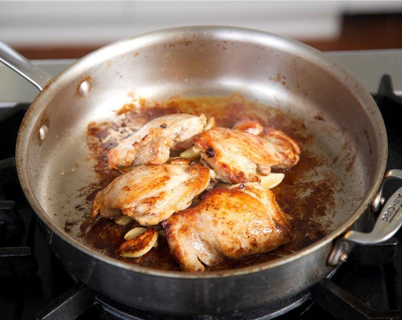 step 7 Reduce heat to medium. Bury the garlic cloves under the chicken. Cook for 5 minutes until garlic begins to brown.
