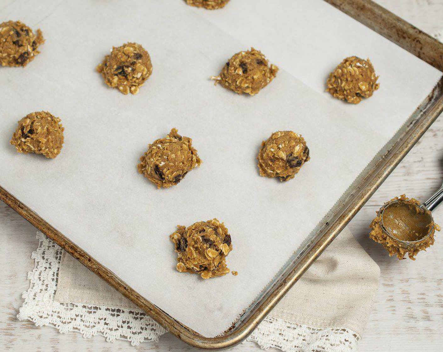 step 6 Using a one-ounce cookie scoop or tablespoon, drop dough onto parchment lined baking trays, spacing 2" apart. Flatten each cookie slightly with damp fingers or palm of your hand. Bake on middle rack for 8-10 minutes.