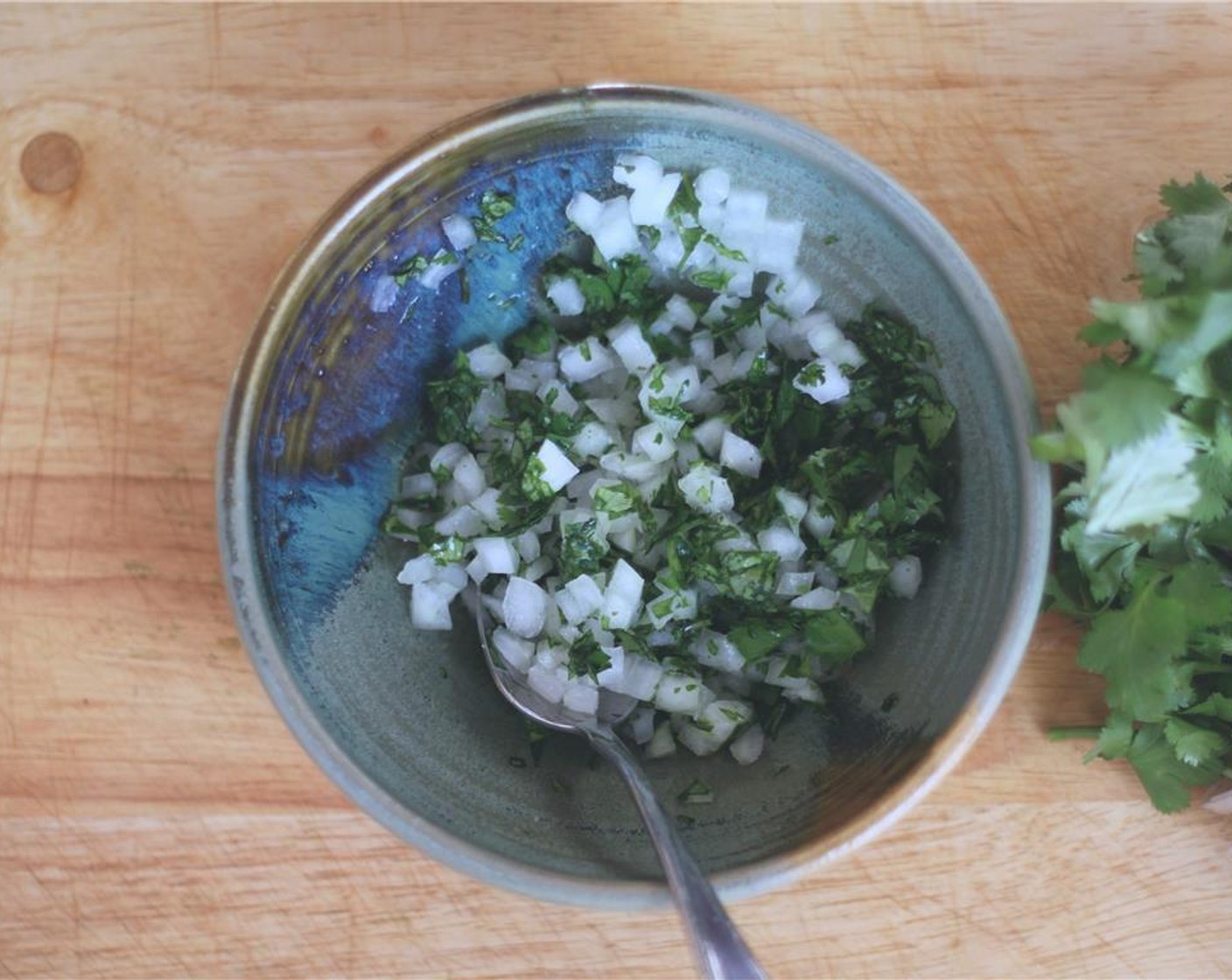 step 5 Meanwhile, make a quick topping by mixing the Yellow Onion (1/2) and Fresh Cilantro (1/4 cup) with juice from Lemon (1) and a little salt.