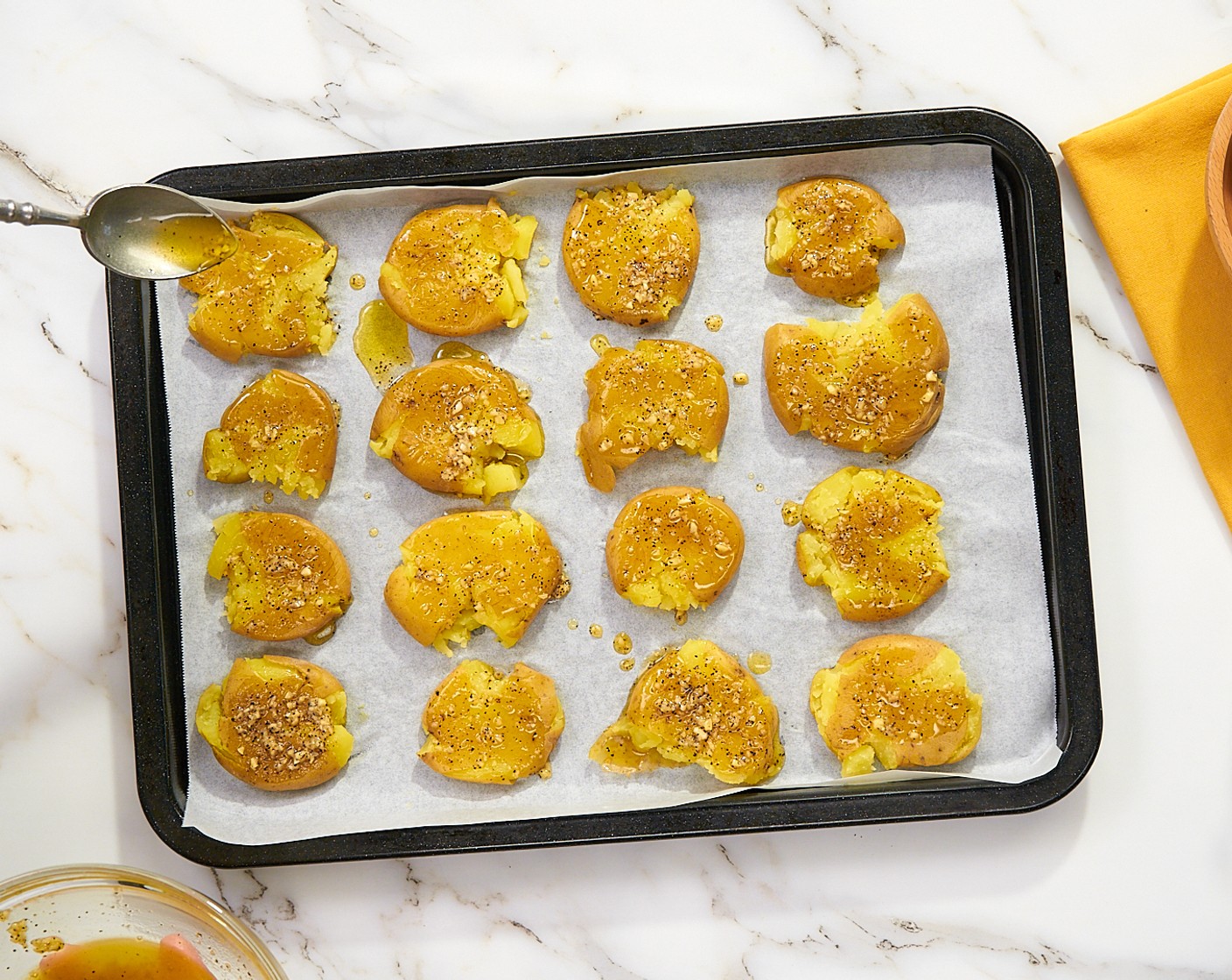 step 6 Als Nächstes die Kartoffeln mit dem Knoblauch-Mix beträufeln. Das Blech in den vorgeheizten Ofen geben und bei 200 Grad Celsius für 15–25 Minuten goldbraun und knusprig backen.