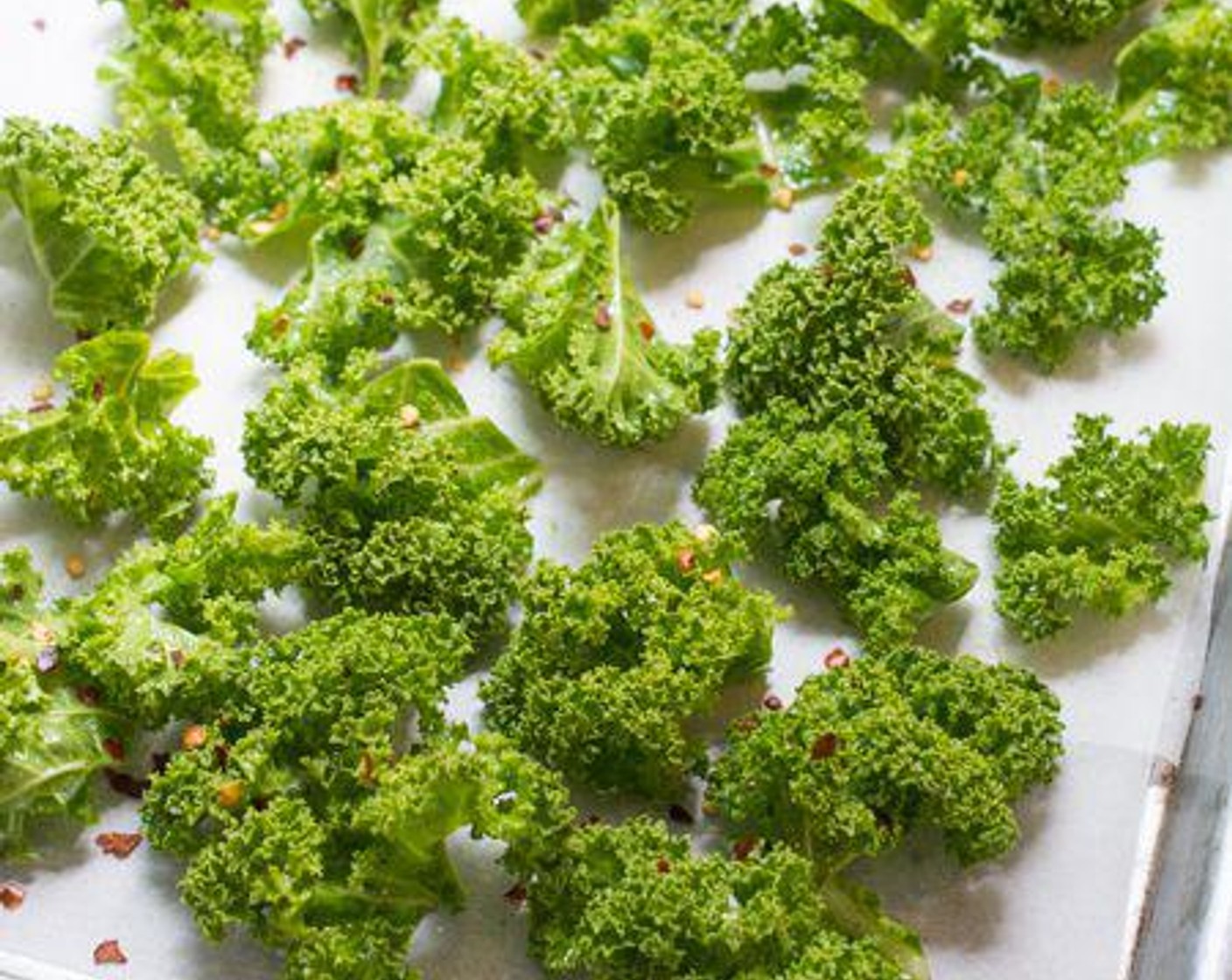 step 5 Line a baking tray with parchment paper, then arrange the kale leaves on the sheet in a single layer. Sprinkle Salt (1/2 tsp) over the kale leaves, followed by Crushed Red Pepper Flakes (1/2 tsp).