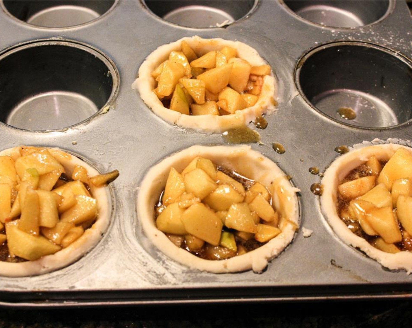 step 4 Add Granny Smith Apples (3) and Macintosh Apples (2) and stir until coated in mixture. Scoop filling into the muffin tins.