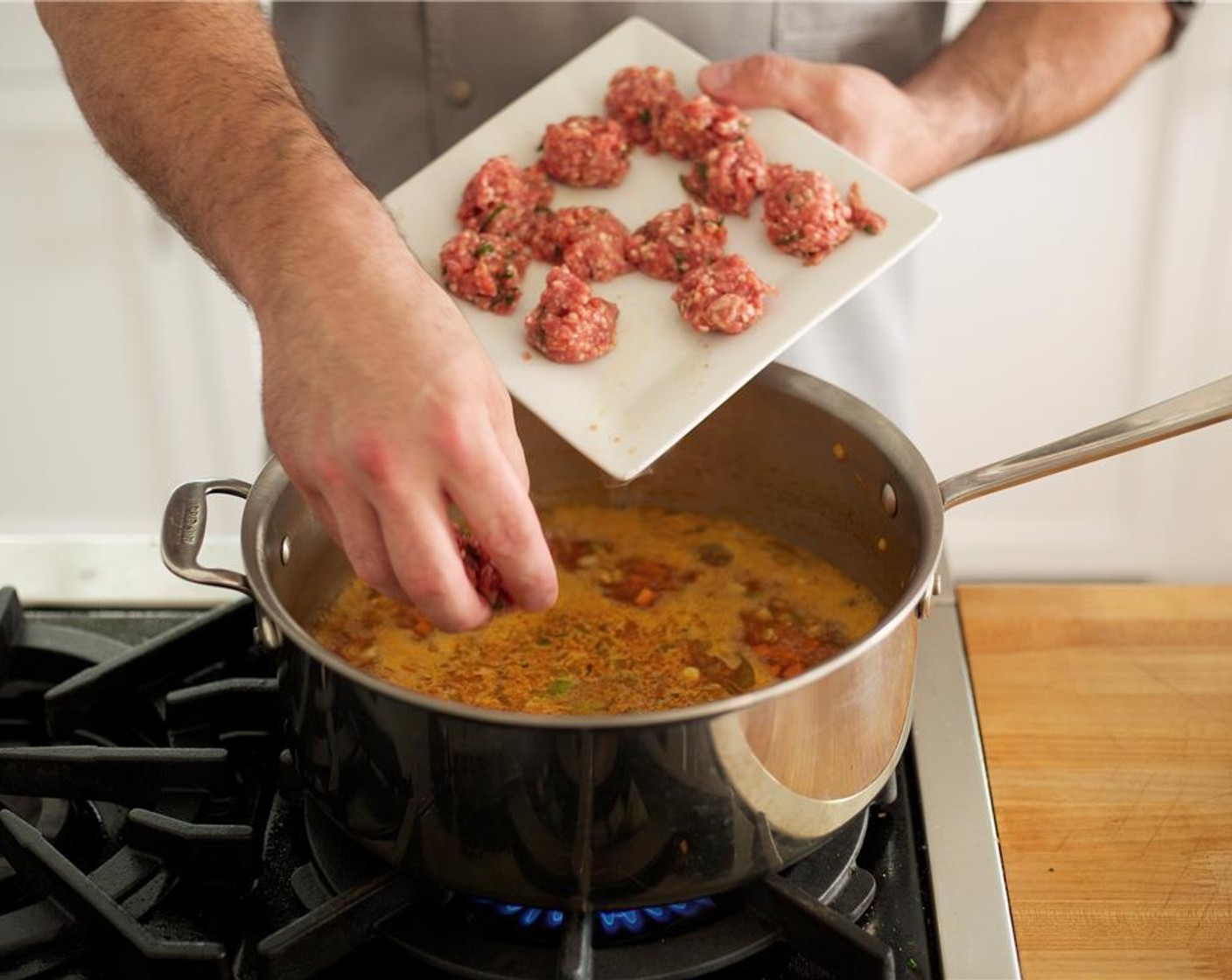 step 10 Carefully add the meatballs to the soup. Add the Serrano Chili (1). Bring back to a boil and reduce heat to medium. Cook for thirteen minutes, stirring occasionally. Using a ladle, skim the fat off the top of the soup and discard.