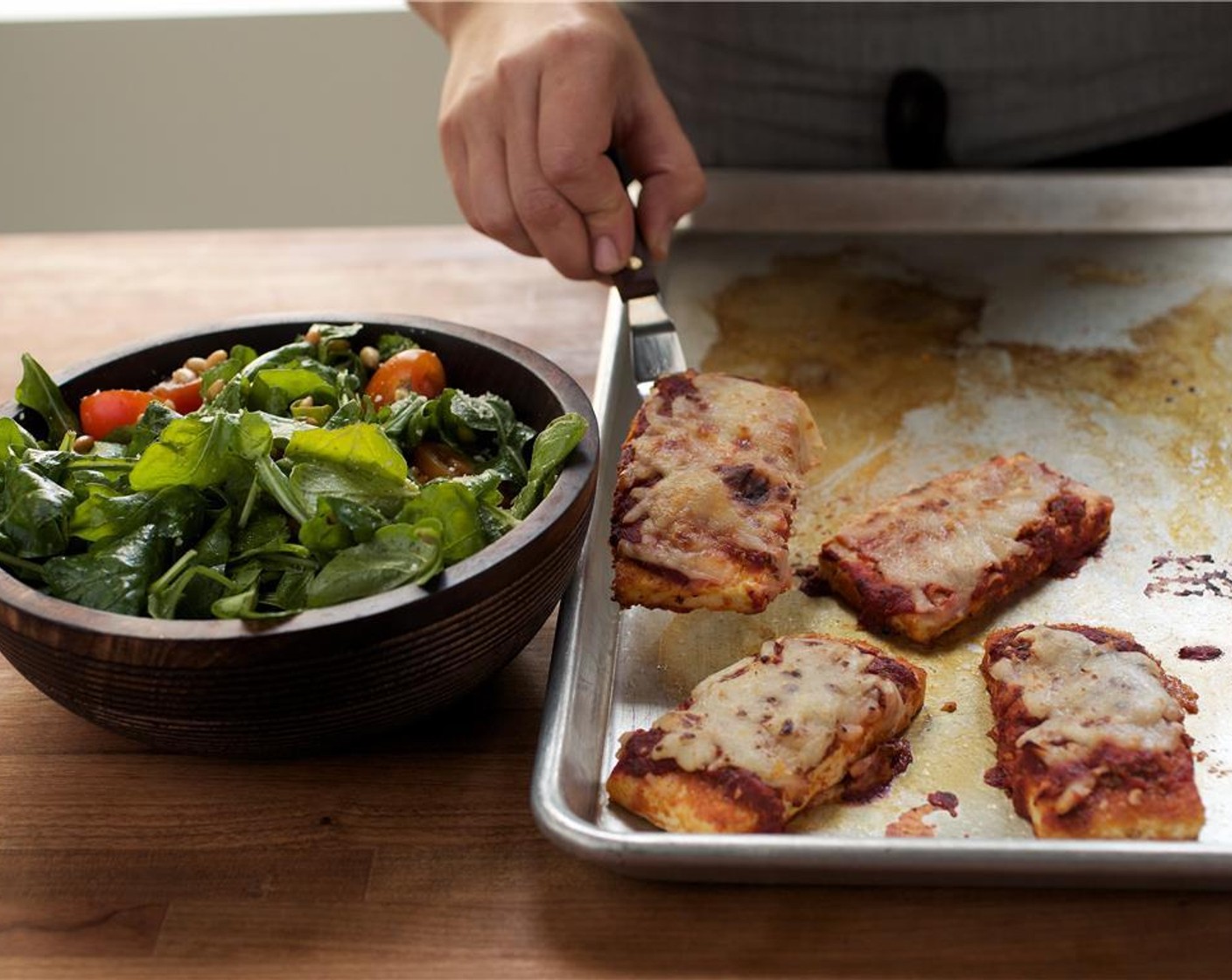 step 10 Evenly distribute the tofu Parmigiana in the center of two plates. Place arugula salad in two separate bowls on the side.