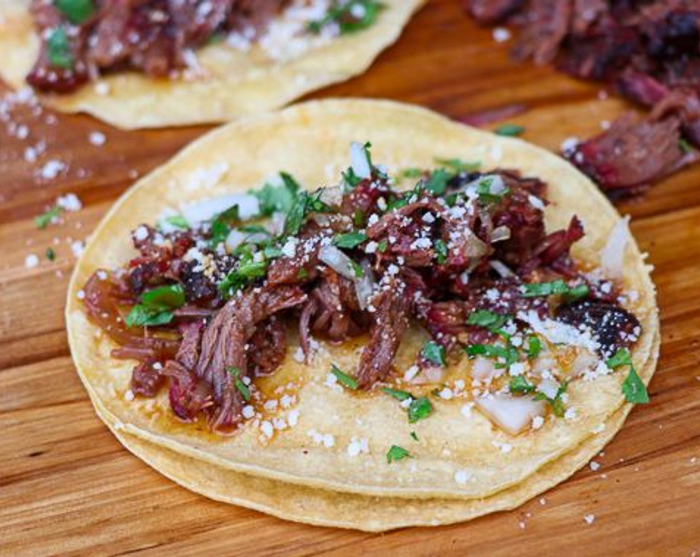 step 7 To build tacos: warm Small Corn Tortillas (12) on grill or stove top. Place shredded beef cheek on tortilla and top with White Onion (1), Fresh Cilantro (1 bunch) and Cotija Cheese (1/2 cup). Dress with a drizzle of braising liquid and serve.