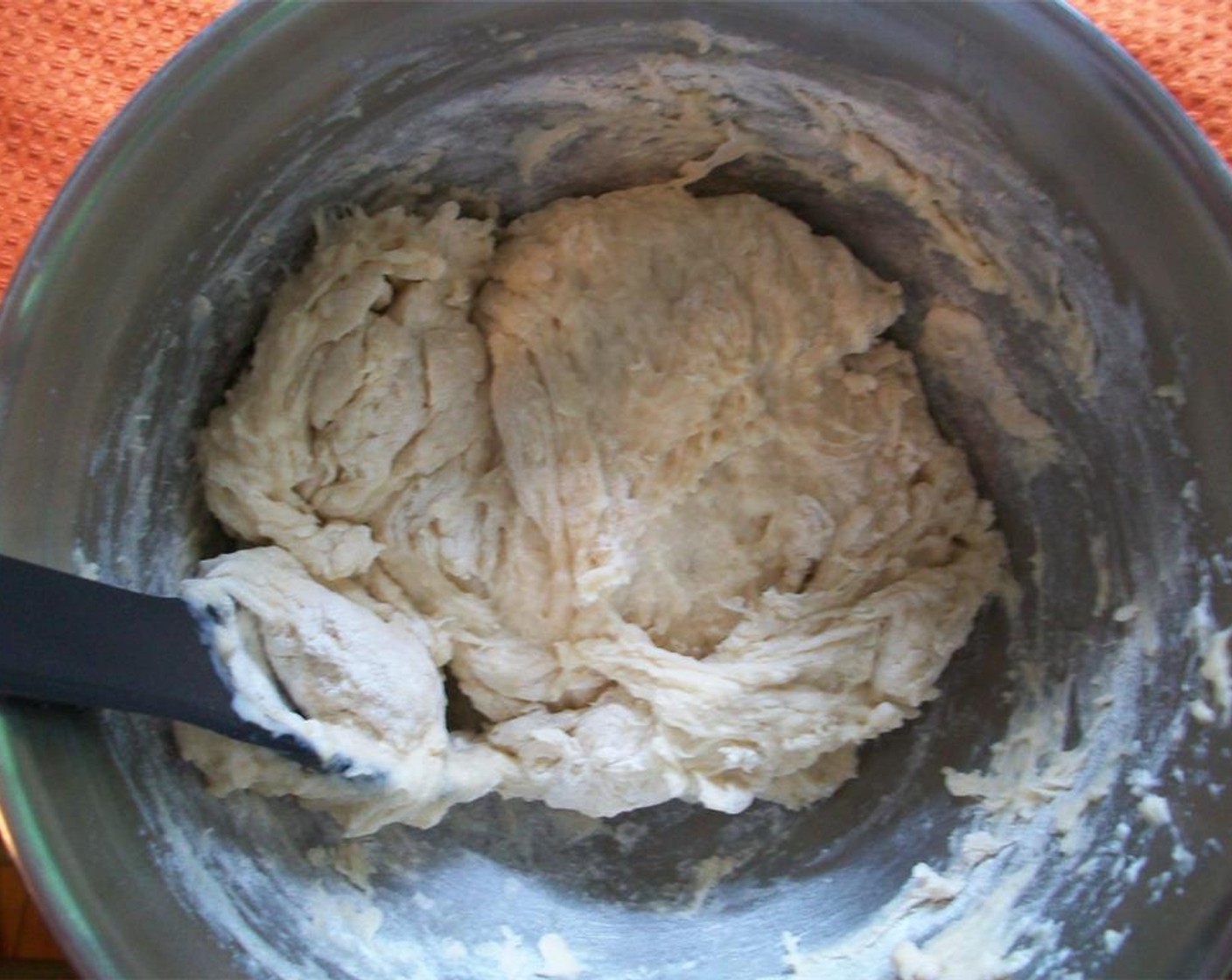 step 2 Make a well in the flour and pour liquid into it. Using a wooden spoon, mix until a slightly shaggy and sticky dough forms.