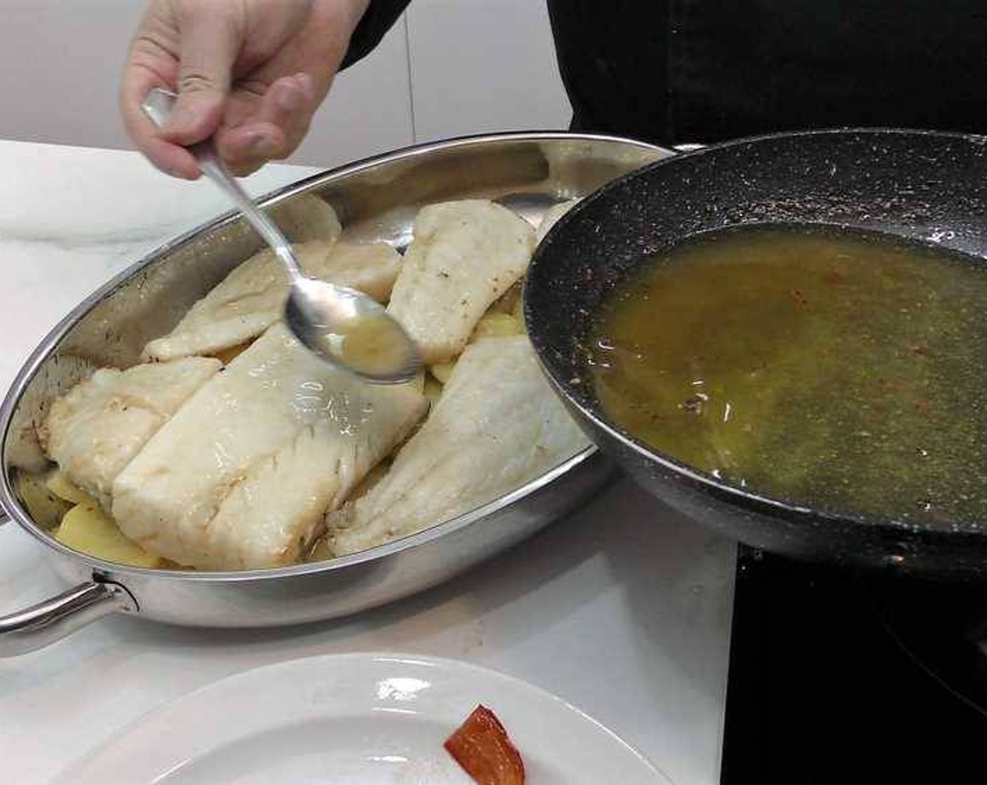 step 13 Place the cod fillets over the potato slices in the baking pan. Spoon some of the frying oil used for the cod on top.