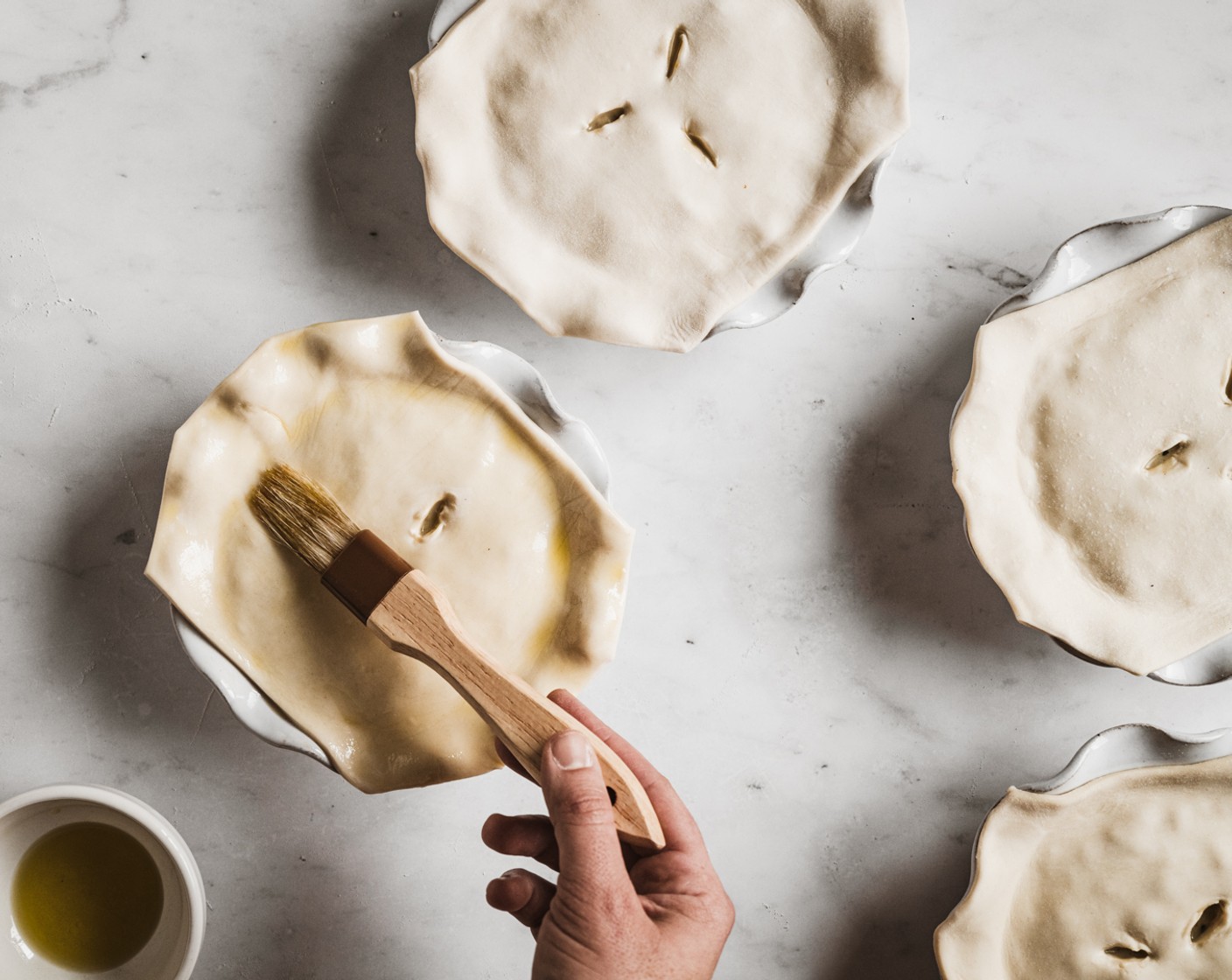 step 17 Place pastry over the filled baking dishes. Brush with Olive Oil (1 Tbsp), and cut 2 or 3 slits into the pastry with a sharp knife to allow pies to vent while baking.