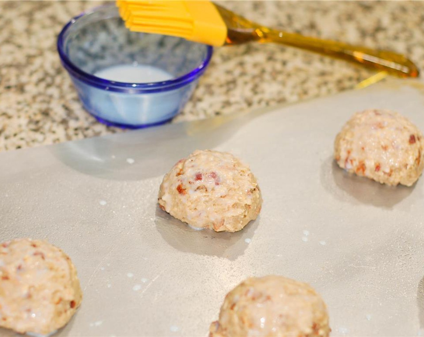 step 5 With a large scoop, place dough onto a greased cookie sheet. Brush the tops and sides of each scone with milk before placing in oven. Bake 13 minutes. Remove from oven and transfer to cooling rack.